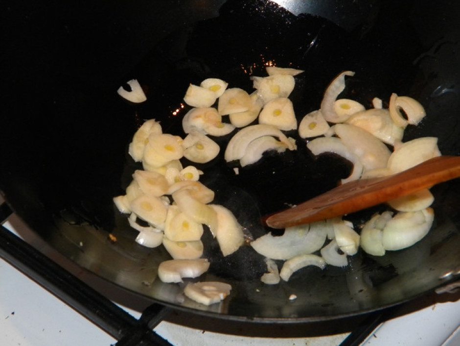Sakarsētā eļļā wok pannā ātri apcepina sīpolus un ķiplokus,...
