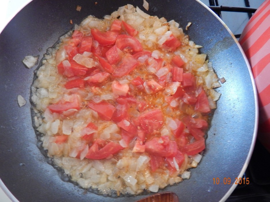Pievieno sīpoliem tomātu un turpina cept.